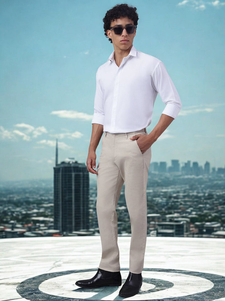 Man in a white shirt and beige pants standing on a rooftop with a cityscape in the background