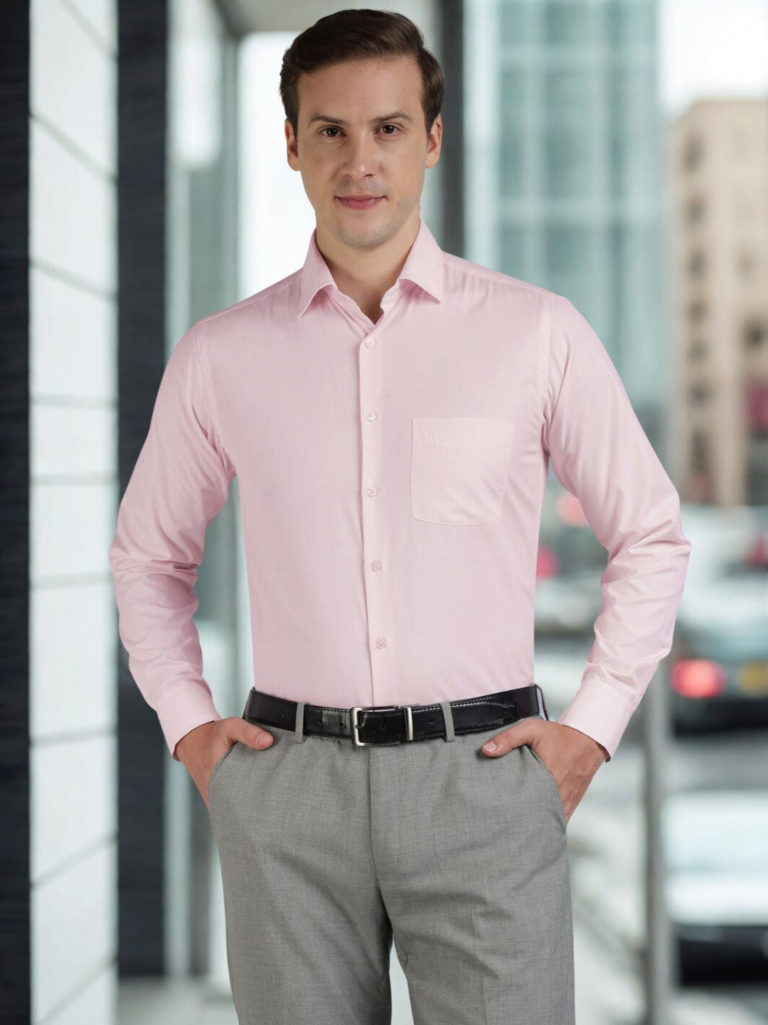 Man wearing a pink dress shirt and gray pants standing in an urban setting.
