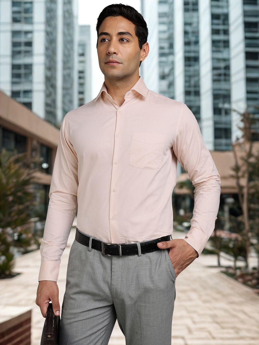 Man wearing a light pink dress shirt and gray pants in an urban setting