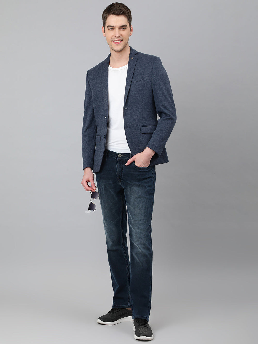 Man wearing a navy blue slim fit casual blazer over a white T-shirt and dark jeans