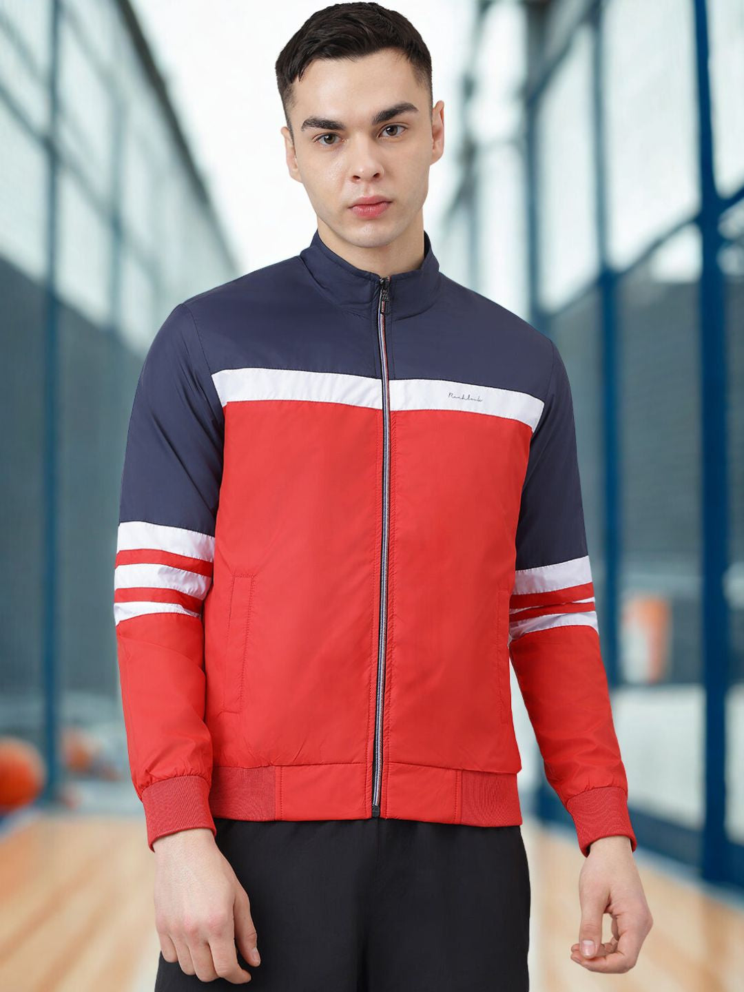 Person wearing a red and navy jacket with white accents indoors.