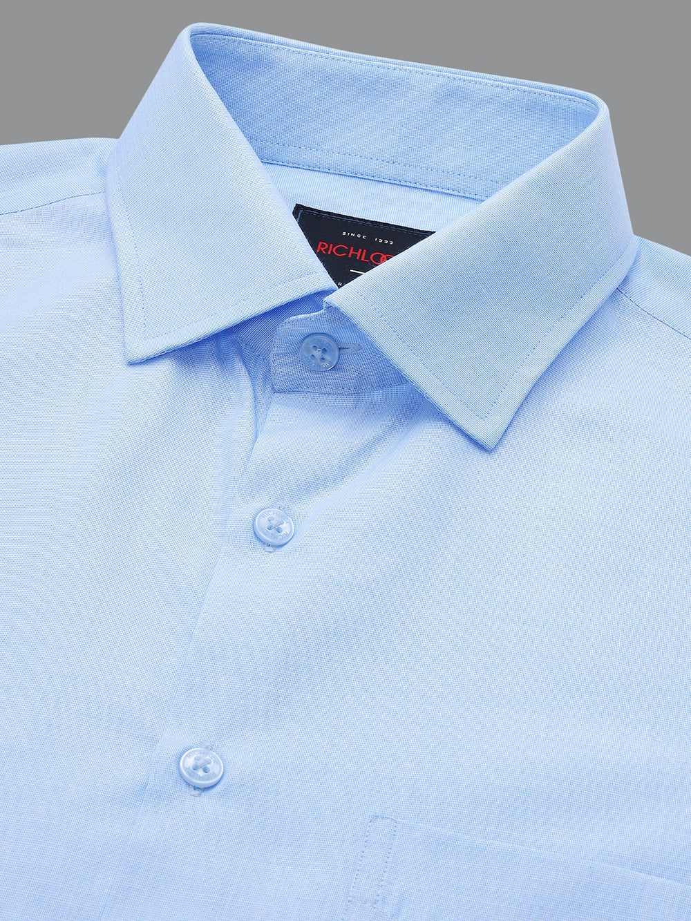 Close-up of a light blue dress shirt with collar and buttons on a gray background
