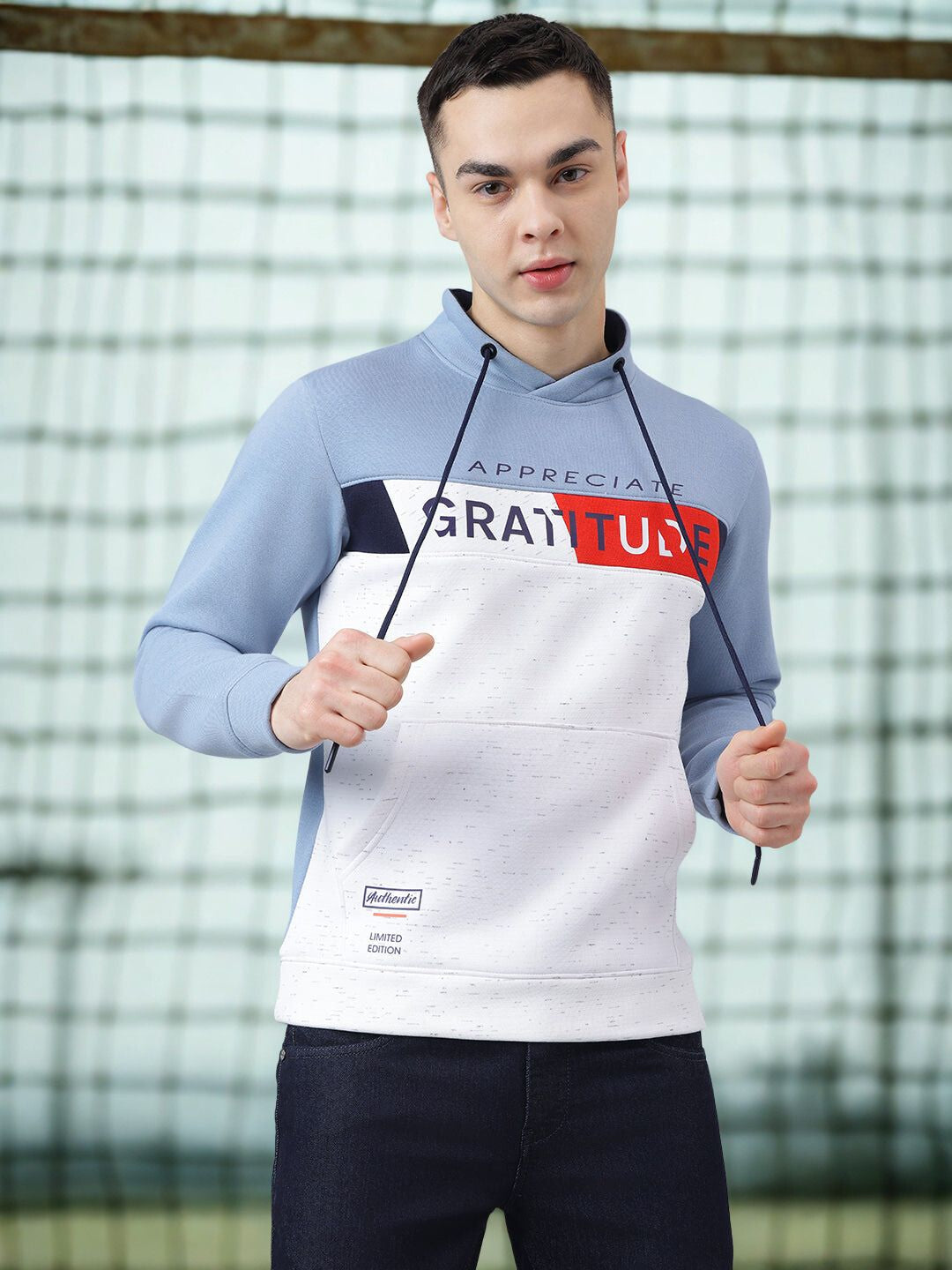 Person wearing a hoodie with 'Appreciate Gratitude' text against a netted background