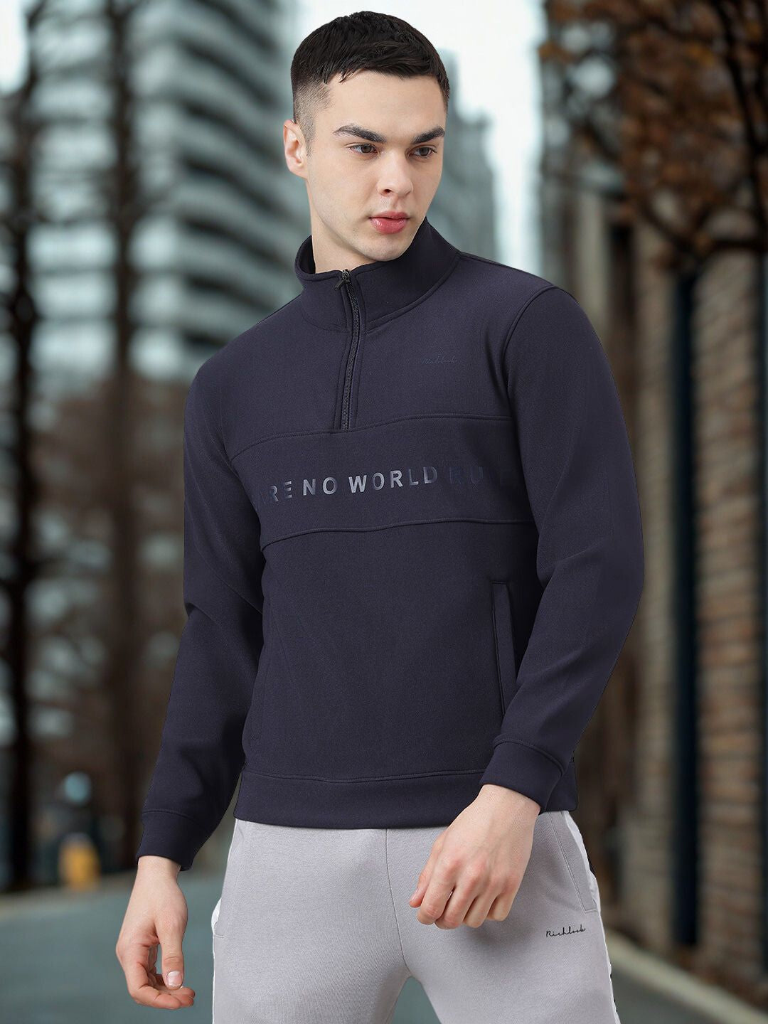 Man wearing a navy blue pullover with 'FEND WORLD' logo in an urban setting